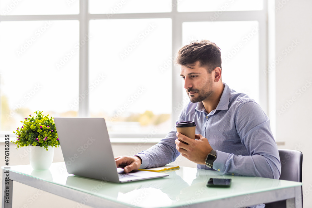 Handsome young businessman working with laptop in office Handsome young businessman working with laptop in office
