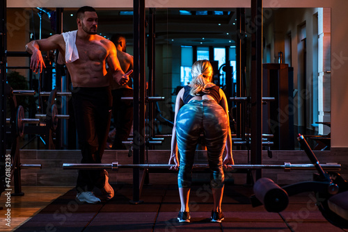 Couple training with barbell in gym. Muscular trainer man training woman with barbell. Personal trainer fitness instructor. photo