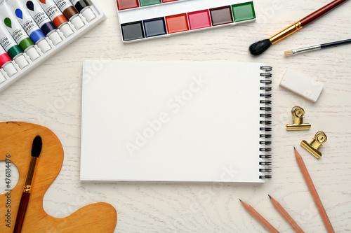 Canvas Print Flat lay composition with blank sketchbook on white wooden table