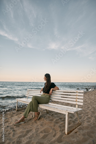 Attractive brunette sits on the sand beach. Concept of serenity at the beautiful place near the sea © AlexGo
