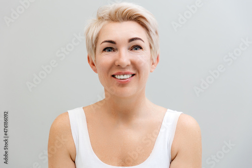 Portrait of an adult happy beautiful woman with blonde hair. Gray background. The concept of psychology and positive emotions