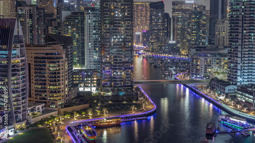 Dubai Marina with several boat and yachts parked in harbor and skyscrapers around canal aerial night timelapse. © neiezhmakov