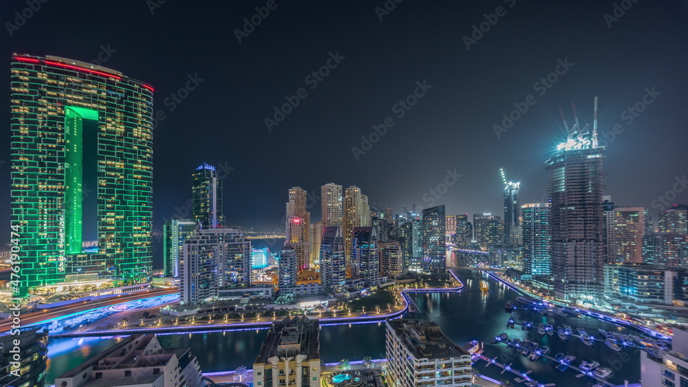 Dubai Marina with several boat and yachts parked in harbor and skyscrapers around canal aerial all night timelapse. Dubai Marina with several boat and yachts parked in harbor and skyscrapers around canal aerial all night timelapse.