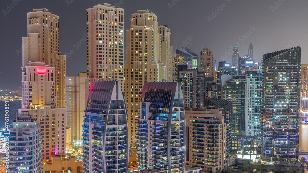 Dubai Marina skyscrapers and JBR district with luxury buildings and resorts aerial timelapse during all night with lights turning off