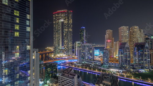 Dubai Marina skyscrapers and JBR district with luxury buildings and resorts aerial timelapse during all night with lights turning off.