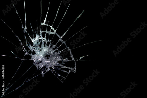 a crack on a broken glass mirror on a black background lines fragments bullet hole