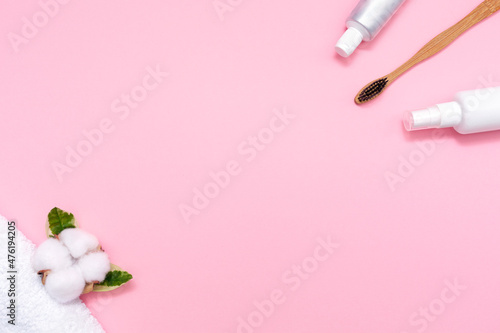 Eco and hygiene. A bamboo toothbrush  mouth freshener  toothpaste and cotton flower with towel. Flat lay. Pink background. Copy space