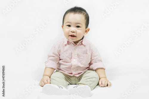 Stylish fashionable kid. Toddler baby boy model in casual clothes.Happy smiling Adorable asian 
child in pink shirt sitting on white bedsheet.Fashion and Style. 