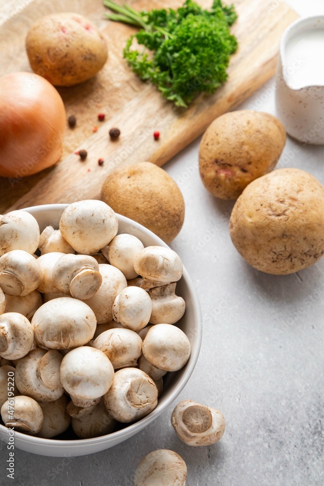 Ingredients for mushroom cream soup on grey table. Champignon, cream, potatoes, onions, parsley, salt and spices on wooden board. Top view. Ingredients for mushroom cream soup on grey table. Champignon, cream, potatoes, onions, parsley, salt and spices on wooden board. Top view.