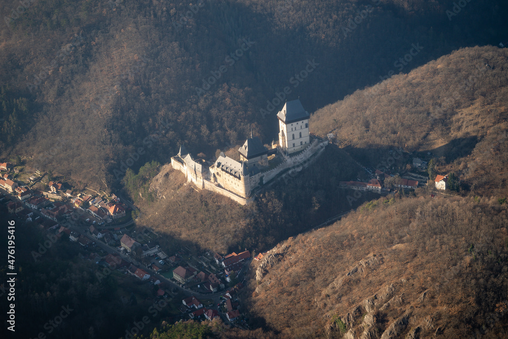 Fototapeta premium Crossing over Karlstejn castle in a propeller plane. Private sightseeing flight. Aerial view of Karlstejn castle on hilltop above village of same name, Czech Republic