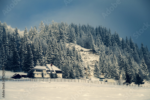 Building in a snow-covered mountainous landscape against a cloudy sky in Ciucas Mountains, Romania photo