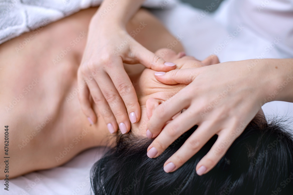 Face and head massage for a young woman. Cosmetology procedures for face and body skin. Alternative medicine. Skin care in adulthood. Horizontal photo of people. Face and head massage for a young woman. Cosmetology procedures for face and body skin. Alternative medicine. Skin care in adulthood. Horizontal photo of people.