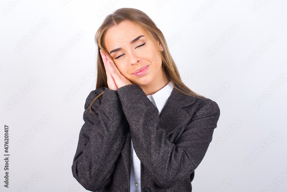 Young business woman wearing jacket over white background leans on pressed palms closes eyes and has pleasant smile dreams about something Young business woman wearing jacket over white background leans on pressed palms closes eyes and has pleasant smile dreams about something