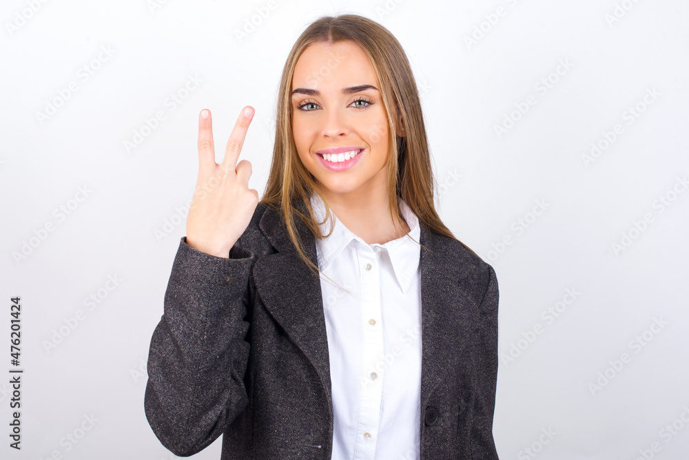 Young business woman wearing jacket over white background smiling and looking friendly, showing number two or second with hand forward, counting down Young business woman wearing jacket over white background smiling and looking friendly, showing number two or second with hand forward, counting down