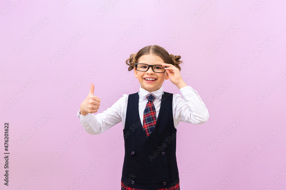 a schoolgirl with glasses on an isolated background. he gives a thumbs up. a schoolgirl with glasses on an isolated background. he gives a thumbs up.
