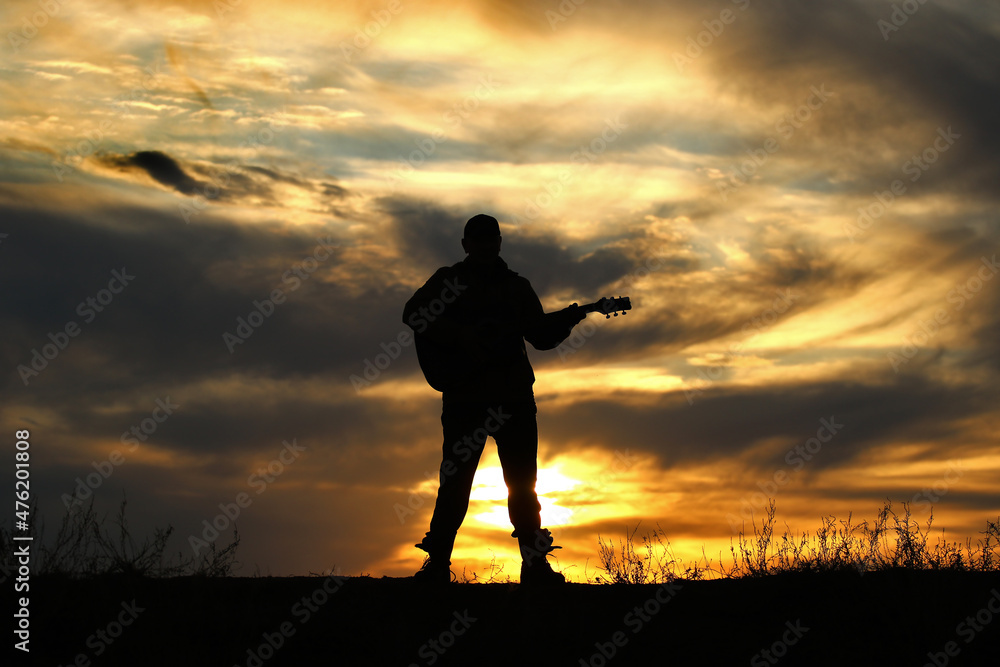 Silhouette of a man with a guitar on a sunset background