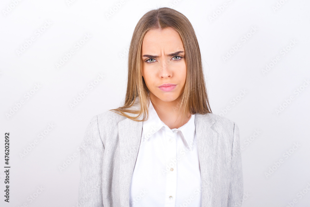 Young business woman wearing jacket over white background Pointing down with fingers showing advertisement, surprised face and open mouth