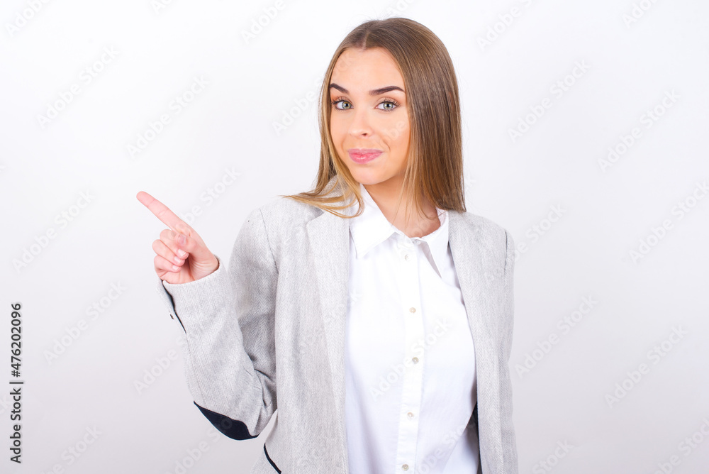 Young business woman wearing jacket over white background points to side on blank space demonstrates advertisement. People and promotion concept Young business woman wearing jacket over white background points to side on blank space demonstrates advertisement. People and promotion concept