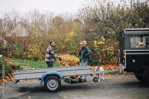 Female and male friends talking while standing by sports utility vehicle