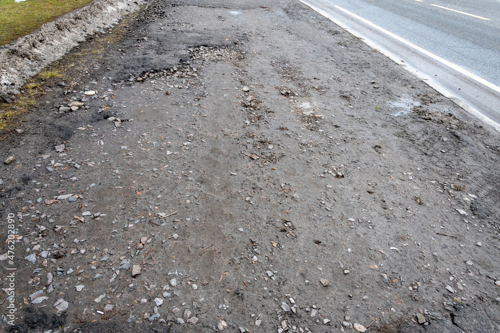 Small potholes on the asphalt road, pits and destroyed road surface.