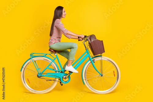 Photo of adorable cute mature lady dressed striped shirt driving bicycle going college empty space smiling isolated yellow color background © deagreez