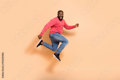 Full body photo of optimistic young guy run wear pullover jeans sneakers isolated on beige background