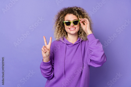 Photo of shiny funny lady dressed hoodie dark glasses showing v-sign isolated purple color background