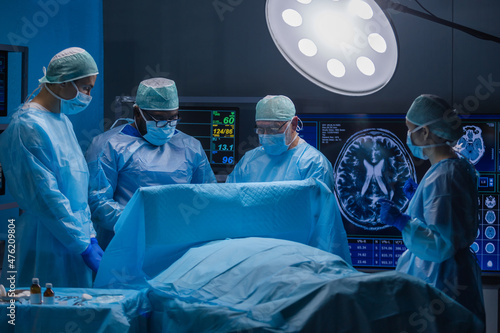 Multiracial team of professional medical surgeons performs the surgical operation in a modern hospital. Doctors are working to save the patient. Medicine, health and neurosurgery. photo