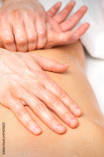 A male physiotherapist stretches the arms on the back of a man lying down  close up