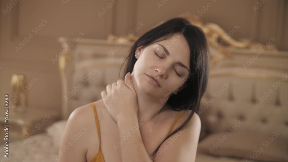 A girl in a nightgown on the bed kneads her neck and puts on a medical mask. Pandemic, covid-19 A girl in a nightgown on the bed kneads her neck and puts on a medical mask. Pandemic, covid-19