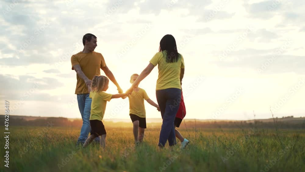 Happy family concept. Group of people hold hands in round dance. Children and parents are play in park on grass. Active lifestyle concept Family on green grass. Happy children play round dance in park Happy family concept. Group of people hold hands in round dance. Children and parents are play in park on grass. Active lifestyle concept Family on green grass. Happy children play round dance in park