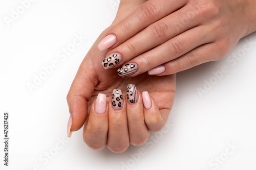 New Year's leopard manicure. Black, gold, beige manicure on long narrowed square nails close-up on a white background. Hands with a gray sweater.