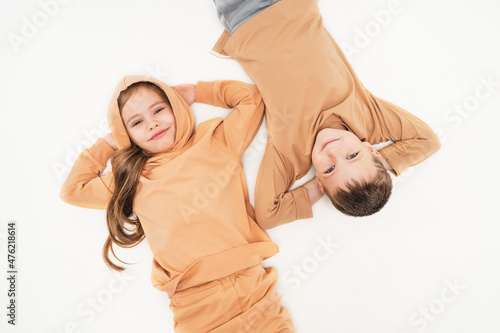 Children in sportswear lie on the floor and look into the frame. Friendship of a boy and a girl since childhood. The brother and sister put their hands behind their heads and rested.