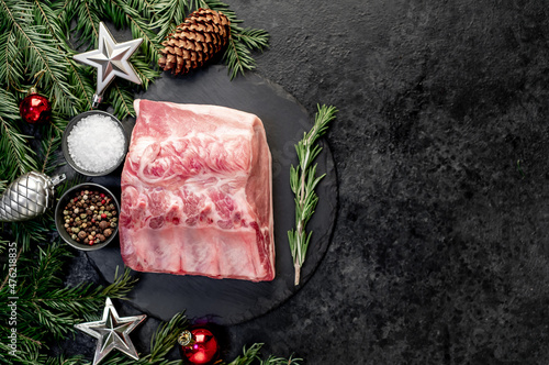 Christmas raw pork steaks, with fir tree and new year decorations on stone background with copy space for your text