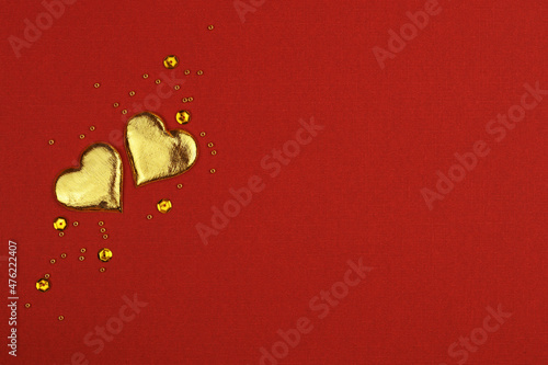 Two golden hearts on red ba...