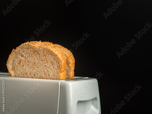 Rich and soft whole wheat bread in the toaster with a black background