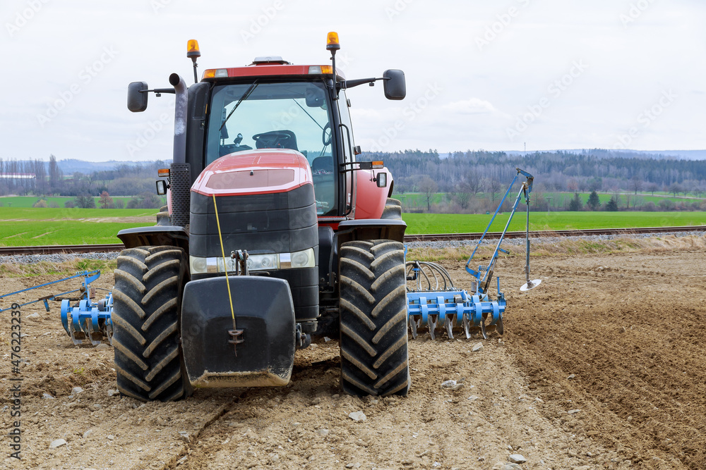 Complex of spring field works. A tractor with a seed drill in a field near the railway. Agro-industrial business. Complex of spring field works. A tractor with a seed drill in a field near the railway. Agro-industrial business.