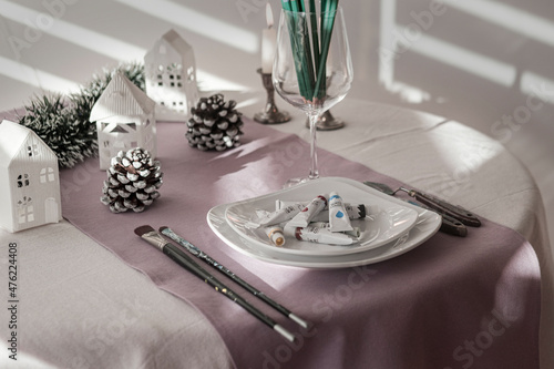 new year food for artist, table served with brushes, spatula, hand made christmas decoration, white and lilac color cloths, pencils, candles, lonely painter celebration dinner photo