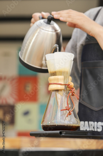Canvas Print Vertical shot of a barista pouring water in a pour-over style coffeemaker on a f