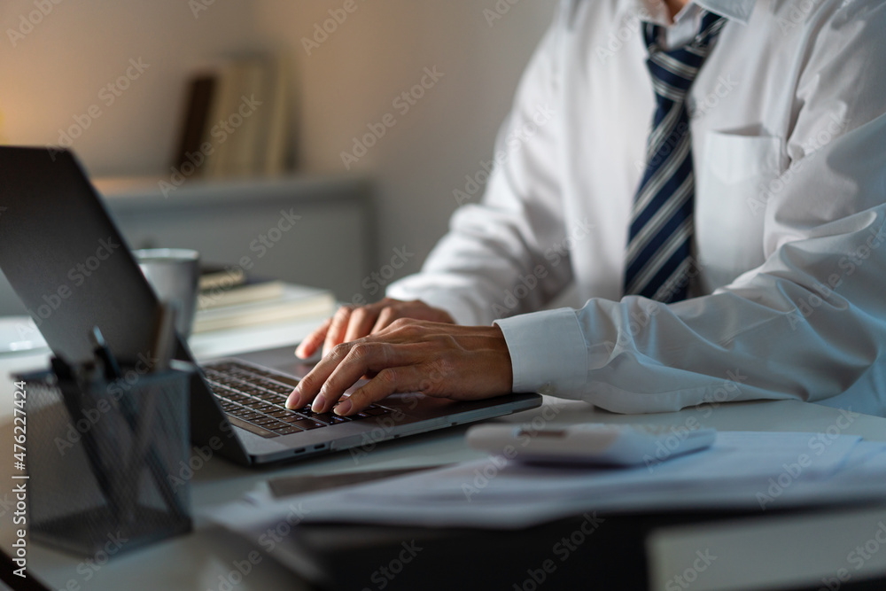 Overwork Concept The man sitting at his desk and focusing on working through his computer laptop Overwork Concept The man sitting at his desk and focusing on working through his computer laptop