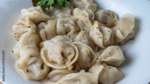 Boiled meat dumplings. Close-up view of russian boiled pelmeni on white plate.