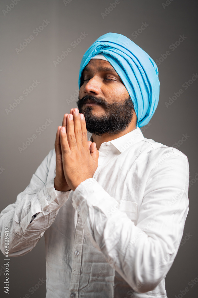 side view shot of indian sikh man doing namste or praying to god on gray background with closed eyes - conept of faith, religious beliefs and Sikhism side view shot of indian sikh man doing namste or praying to god on gray background with closed eyes - conept of faith, religious beliefs and Sikhism