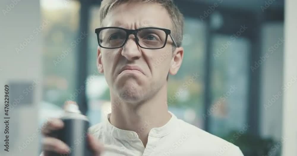 Man smelling a bad odor and spraying air freshener Man smelling a bad odor and spraying air freshener