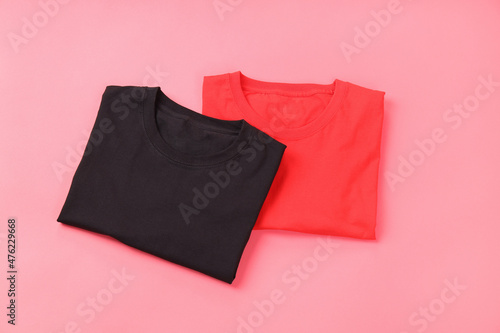 Folded black and red t-shirts on pink background