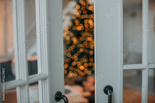 Blurred Decorated Christmas tree with gift boxes from door at bright interior