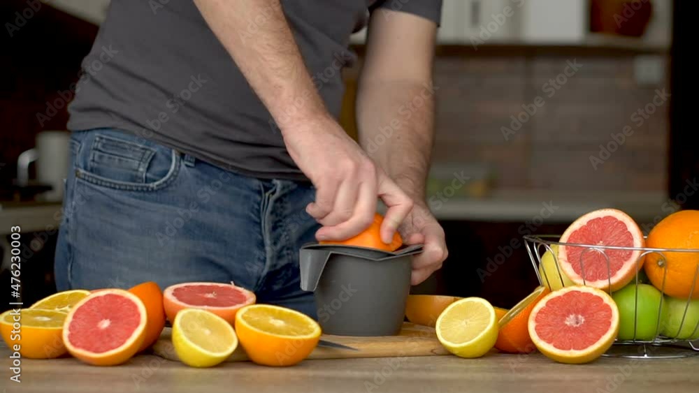 A man is squeezes orange juice with citrus juicer. Close-up of hands, oranges, juicer, healthy lifestyle A man is squeezes orange juice with citrus juicer. Close-up of hands, oranges, juicer, healthy lifestyle