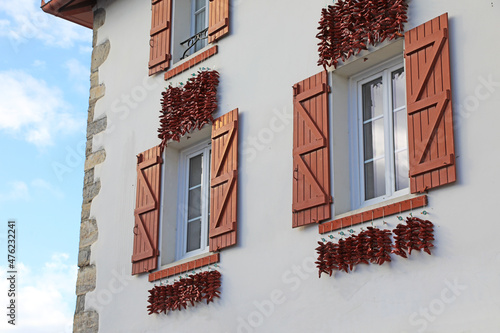 Canvas-taulu espelette pimientos rojos colgados el la fachada de una casa con ventanas rojas