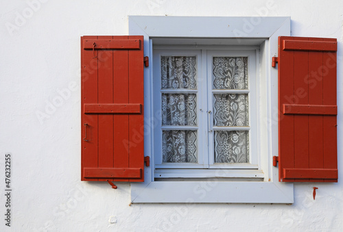 ventana gris y contraventana roja con cortina de encaje casa de espelette pueblo vasco francés francia 4M0A8126-as21 photo