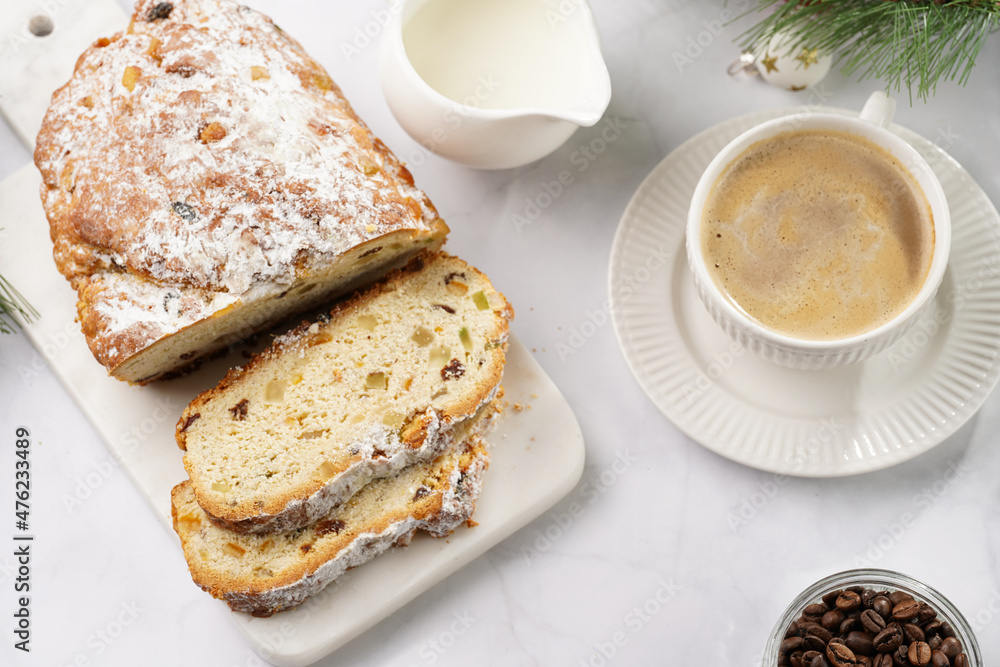 White porcelain cup with coffee cappuccino on a white saucer plate and christmas pastry stollen on a marble table White porcelain cup with coffee cappuccino on a white saucer plate and christmas pastry stollen on a marble table