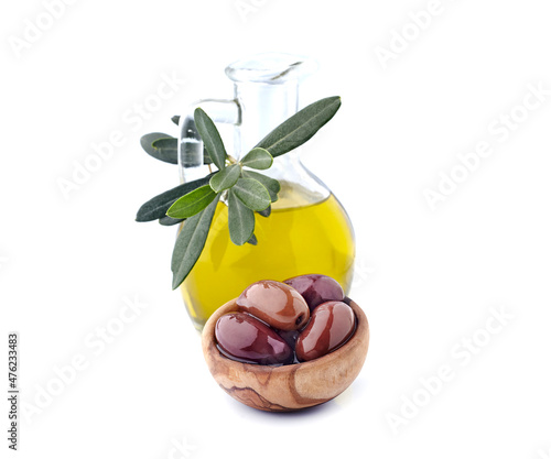 Red olives on white background with oilive oil closeup. Olives Kalamata with leaves in wooden bowl. photo